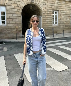 Détails de broderie sur gilet court blanc sans manches avec motifs floraux bleus texture