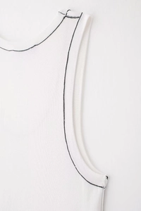 Detail of white knit vest featuring contrast black stitching on the armhole and shoulder