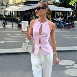 Haut licou rose avec nœuds et pantalon blanc à jambes larges dans un cadre urbain chic