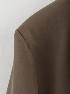 Close-up detail of dark brown blazer shoulder seam and premium woven fabric texture
