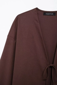 Détail d'une veste kimono marron foncé en lin avec col en V et fermeture à nouer