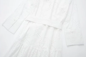 Close-up of white midi dress showing delicate eyelet embroidery and a buttoned pleated cuff