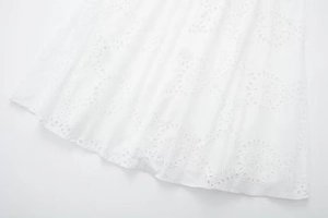Close-up of white eyelet embroidery midi dress featuring intricate floral lace and hem detail