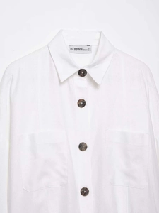 Detail of white cotton blouse showing marble buttons and brand label on collar