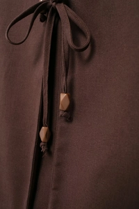 Détail de la texture en coton lin et cordon de serrage avec perles losanges en marron foncé