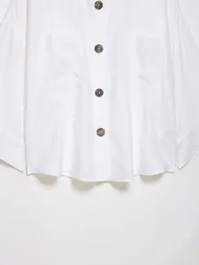 Detail of white batwing sleeve shirt featuring dark tortoiseshell buttons and large pockets