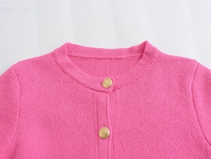 Detail view of pink knit cardigan featuring gold vintage embossed metal buttons
