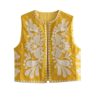 Détail du gilet jaune sans manches avec broderie florale blanche et ouverture frontale