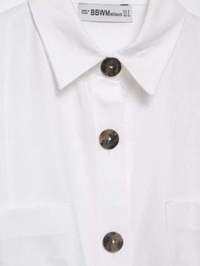 Detail of white cotton shirt featuring a lapel collar, marble buttons and double pockets