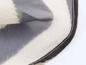 Macro detail of breathable chiffon fabric with abstract grey ink print and rolled hem
