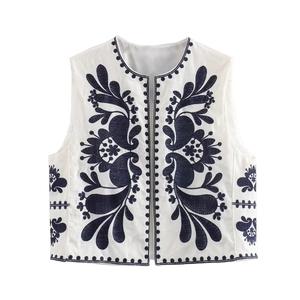 Détail de gilet sans manches avec broderie florale bleu marine sur coton blanc vintage