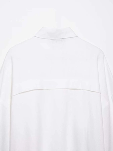 Detail view of the breathable textured fabric and back seam on white batwing sleeve shirt