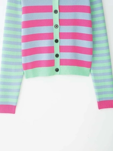 Detail of colorful striped knit cardigan featuring pink and blue tones with black buttons