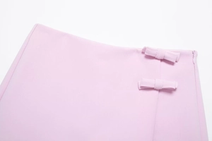 Détail de jupe rose avec deux nœuds en tissu et une fermeture éclair invisible sur le côté