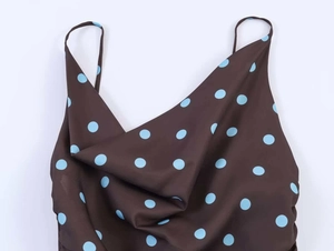Detail of a brown camisole featuring blue polka dots and an elegant cowl neckline