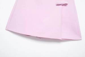Détail d'une jupe-short rose clair à texture plate et nœud décoratif sur le côté