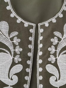 Détail de broderie ethnique blanche sur gilet vert olive avec texture en lin premium