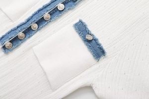 Detail aus weißem Rippstrick mit Denim-Besatz und silbernen Ankerknöpfen