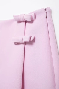 Détail d'une jupe-short rose clair montrant la texture, les nœuds et la fermeture éclair