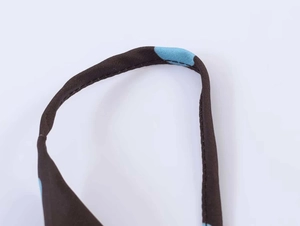 Detailed close-up of blue polka dots on brown woven fabric with reinforced stitching