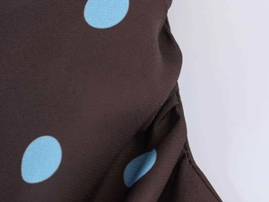Close-up of brown vintage fabric with blue polka dots and a textured crepe finish
