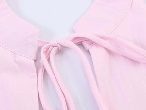 Detailed close-up of light pink poplin fabric featuring a bow tie halter neck design