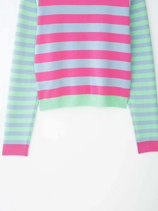 Detail view of the colorful striped knit sweater showing ribbed cuffs and vibrant texture