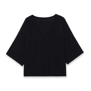 Dettaglio di una maglia nera minimalista con scollo a V e ampie maniche a tre quarti