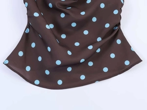 Close-up of brown satin fabric with blue polka dots and smooth stitching details