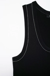 Close-up of black knit tank top featuring contrasting white stitching and a deep U-neck