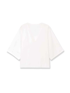 Dettaglio di top in maglia bianca con scollo a V profondo e maniche ampie su sfondo bianco