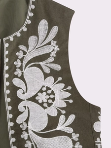 Détail de broderie florale blanche sur gilet sans manches vert foncé au style ethnique