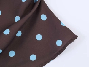 Detail of brown fabric with light blue polka dots featuring clean stitching and soft drape