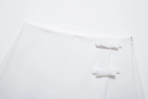 Détail de jupe-short blanche tissée avec petits nœuds et une fermeture éclair invisible