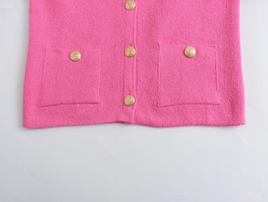 Close-up of bright pink knit cardigan with detailed gold embossed buttons and pockets