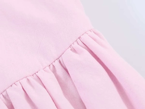 Detailed close-up of pink poplin fabric featuring ruffled textures and fine stitching