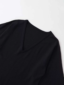 Dettaglio della maglia nera con scollo a V che mostra la trama del tessuto fine