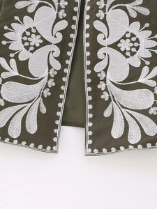 Gros plan sur un gilet sans manches vert olive avec broderie florale blanche détaillée