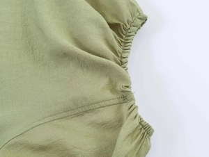 Detail von salbeigrünem Stoff mit feiner Textur, Nähten und elastischen Raffungen