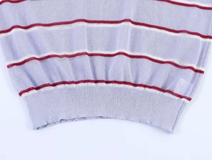 Close-up of lilac knitted sweater featuring crimson stripe patterns and ribbed hem detail