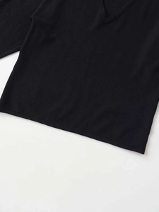 Dettaglio dello scollo a V profondo e del tessuto a maglia su un top nero a maniche corte