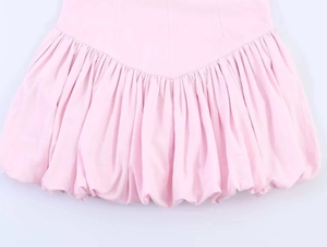 Detail of pink poplin halter dress featuring ruffled hem and balloon silhouette texture