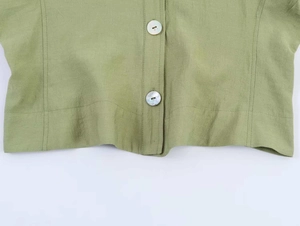 Detail der grünen Leinenbluse mit Perlmuttknöpfen und strukturierter Stoffoptik