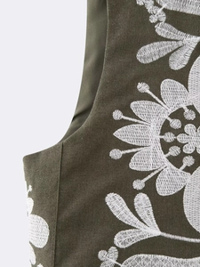 Détail de broderie florale blanche sur gilet sans manches vert olive en coton et lin