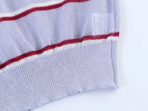 Detailed close-up of ribbed hem on light purple knit top with red and white stripes