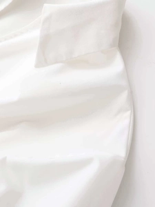 Detailed close-up of white poplin fabric texture and V-neckline stitching of the mini dress