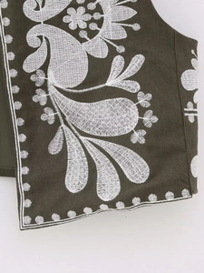 Gros plan de la broderie florale blanche sur un gilet haut de gamme vert olive
