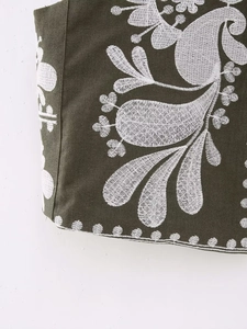 Vue macro du tissu de gilet vert olive avec détails de broderie paisley blancs fins