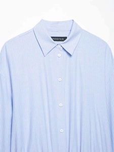 Detail of light blue striped dress collar with white buttons and brand neck label