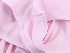 Detail view of pink poplin fabric featuring smocked texture and refined stitching